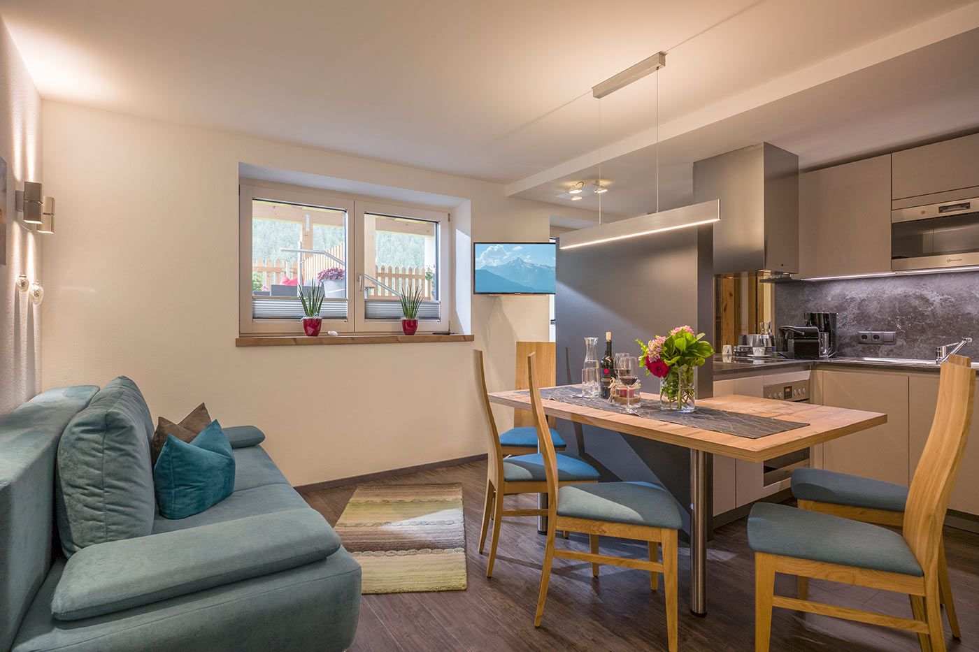 A photo of a living kitchen with a dining table, chairs and a blue sofa