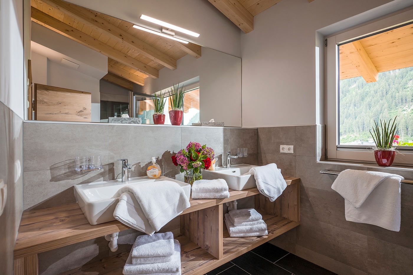 Bathroom with 2 sinks in front of large mirror next to a window
