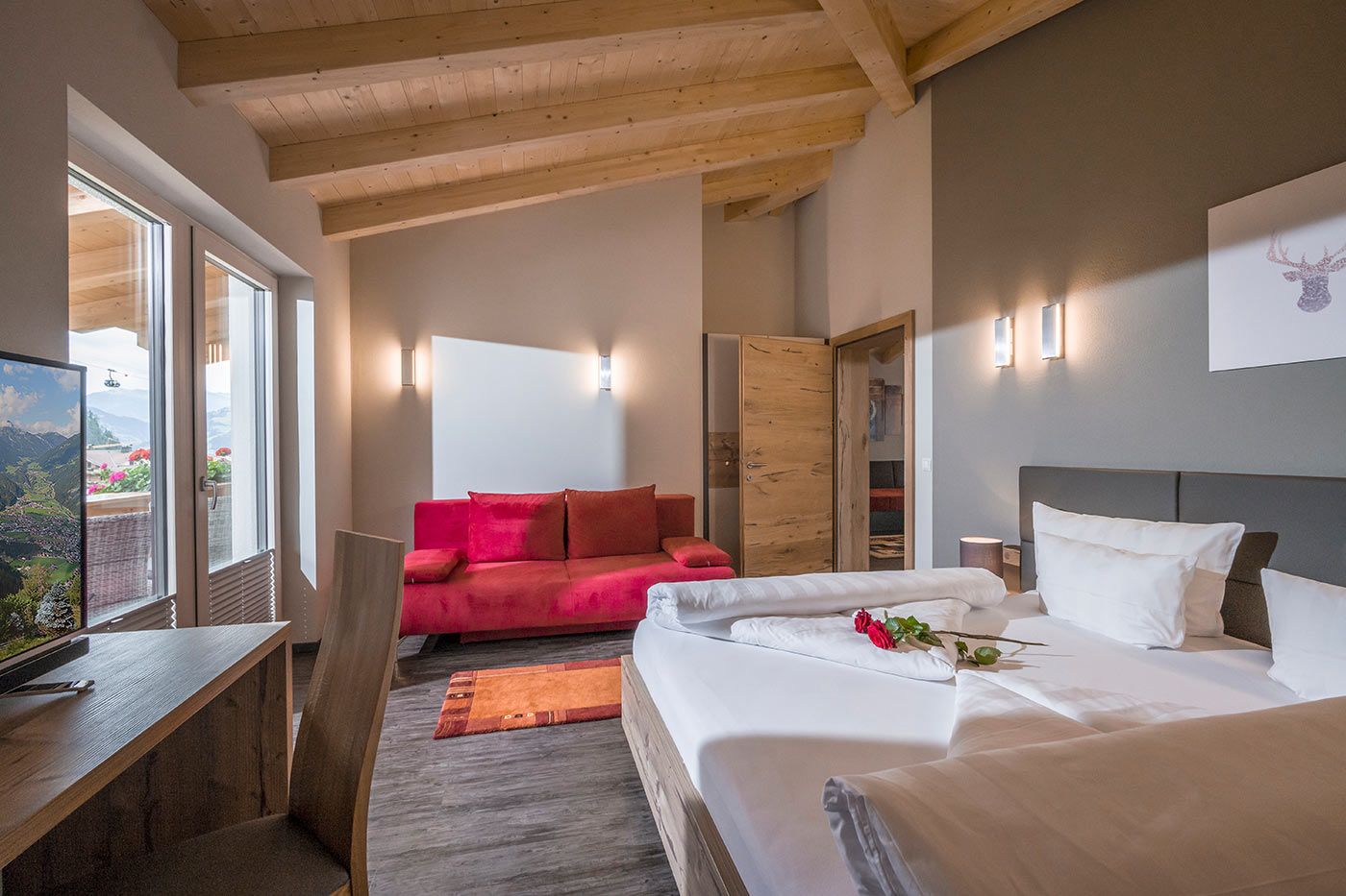 Second bedroom with double bed, red sofa and side-mounted TV