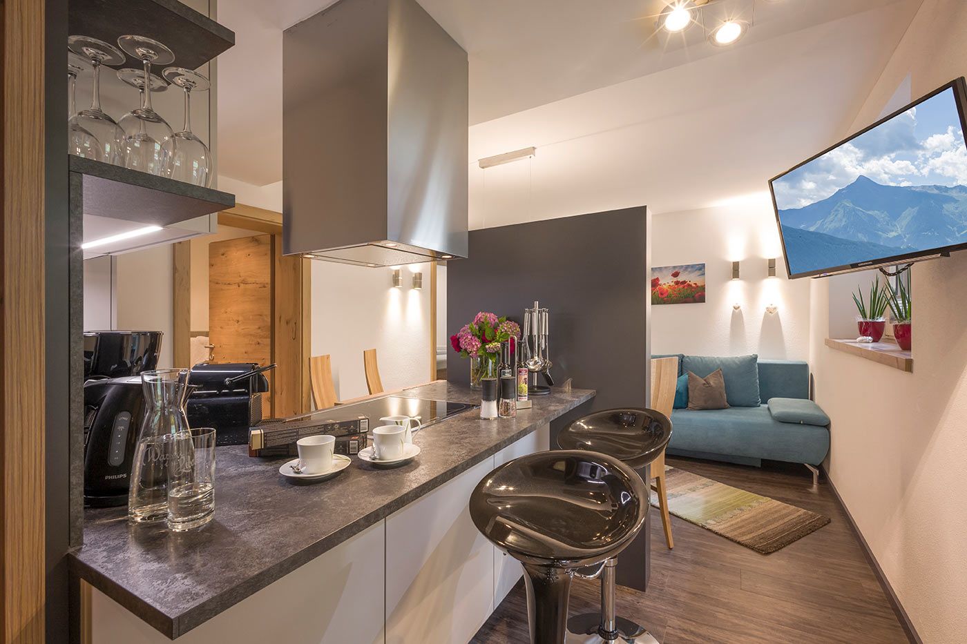 A photo of a kitchen with two chairs, a TV and a blue sofa in the background