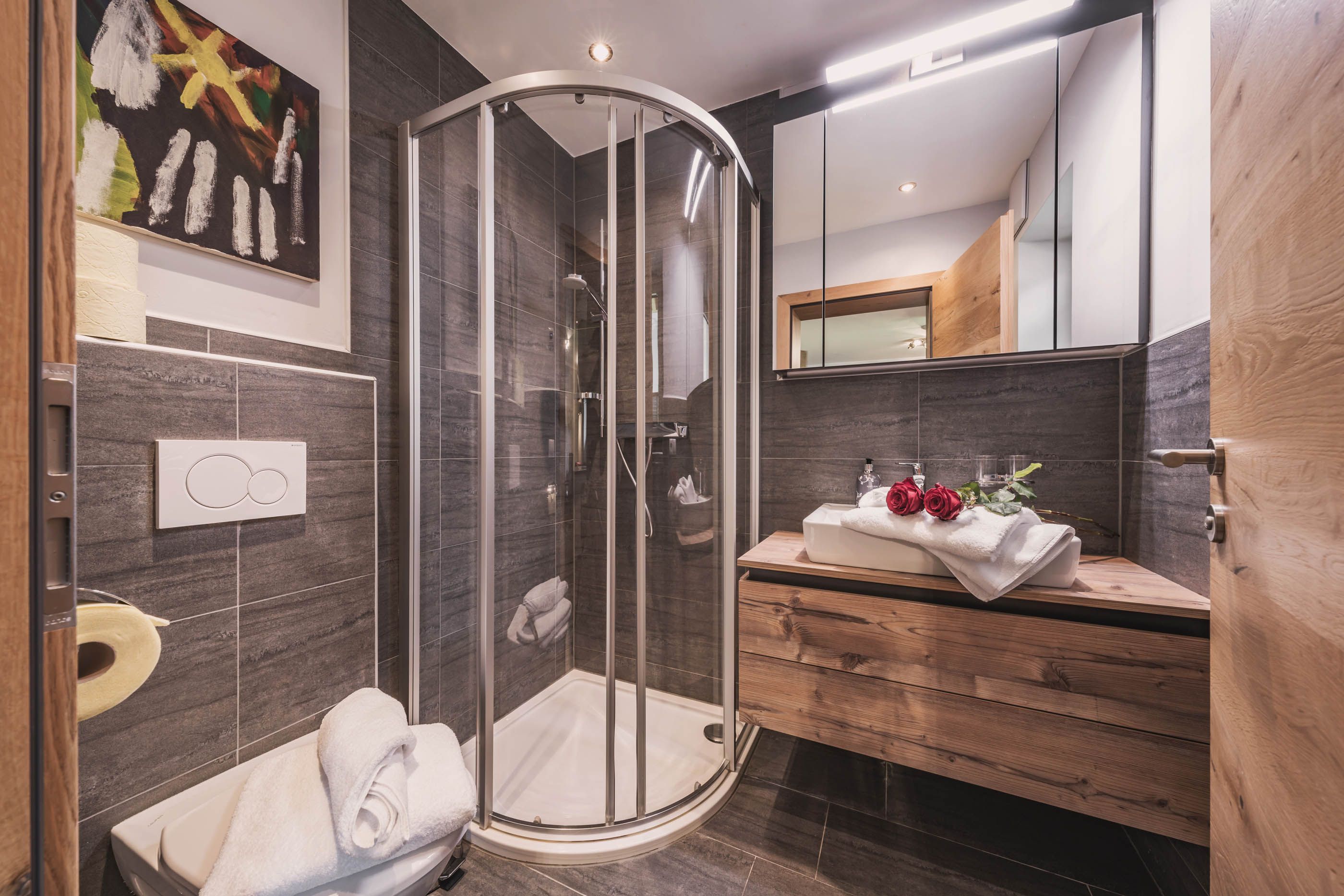 Elegantes Badezimmer mit runder Duschkabine, Holzwaschtisch und dunklen Fliesen