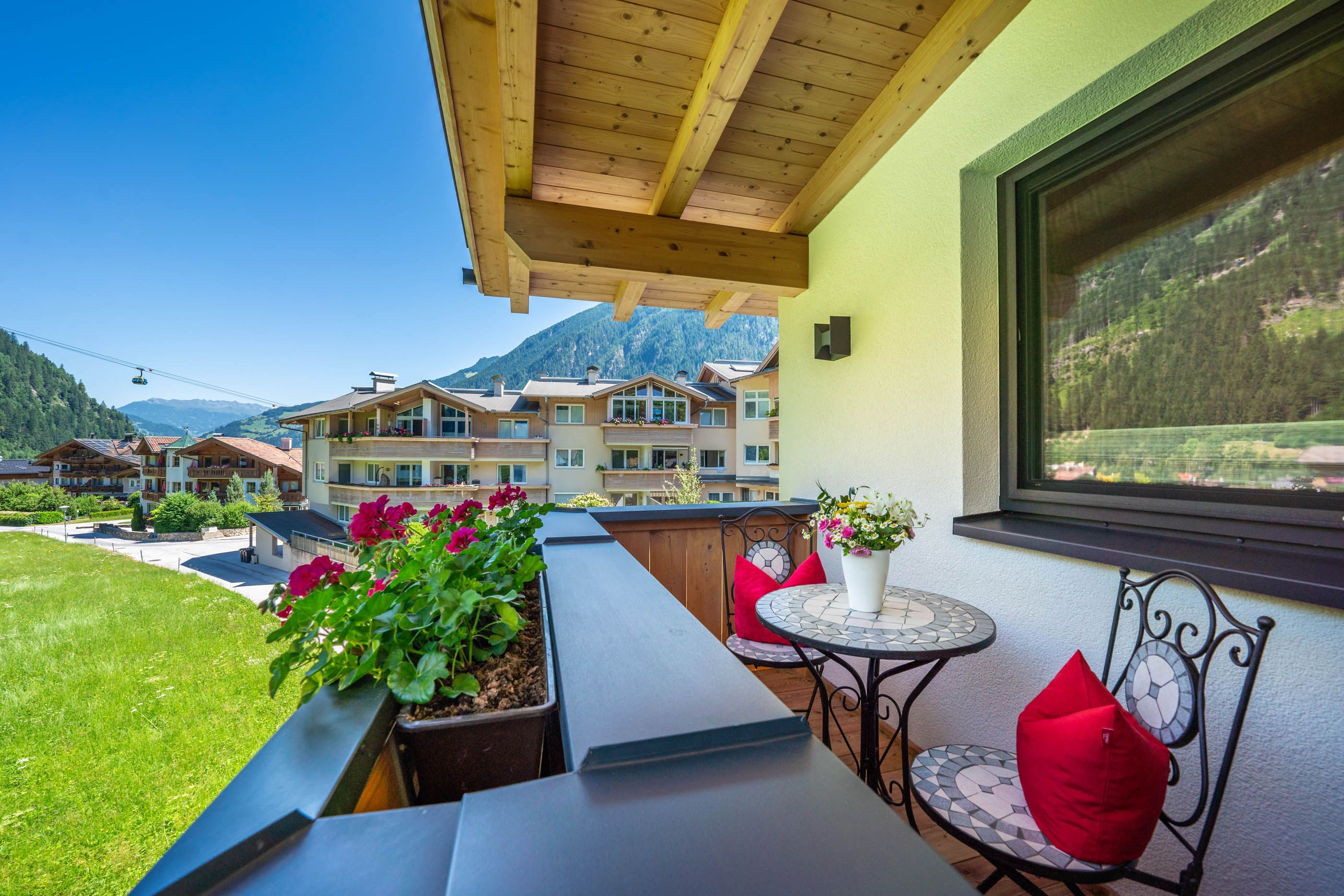 Traumhafter Balkonausblick auf die Berglandschaft mit Tisch, Stühlen und bunten Blumen