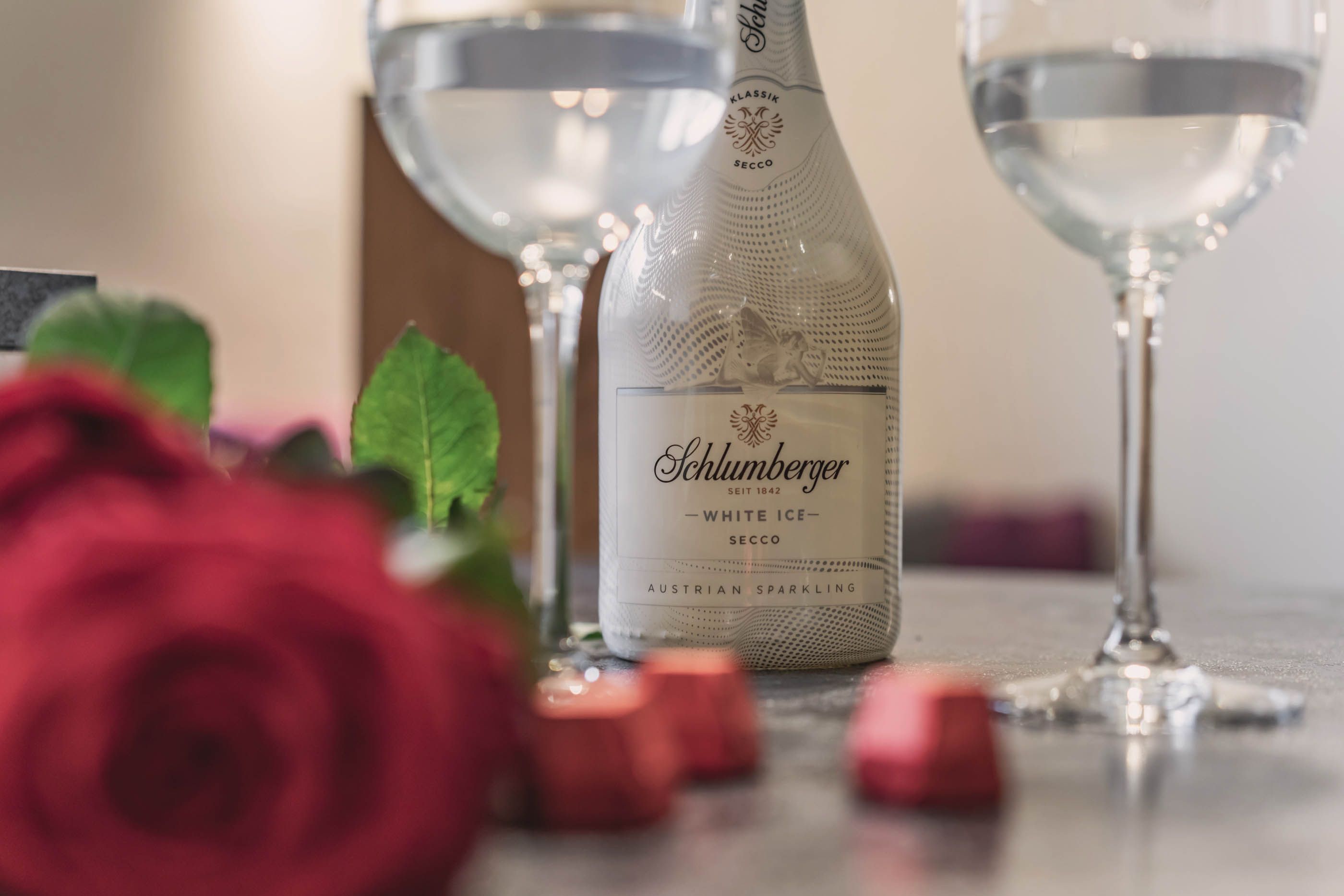 A bottle of Schlumberger sparkling wine with two glasses and red roses as romantic greeting