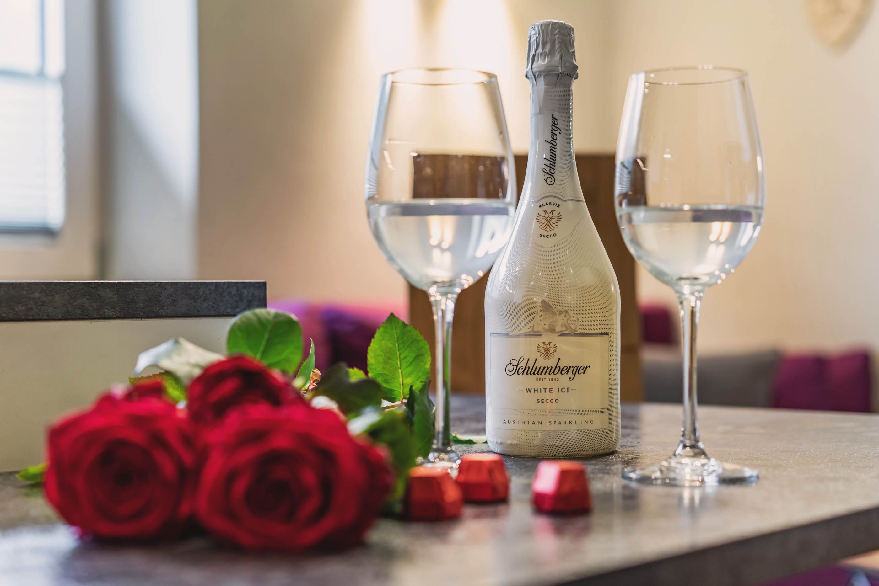 Schlumberger Sekt mit gefüllten Gläsern und roten Rosen für einen romantischen Aufenthalt