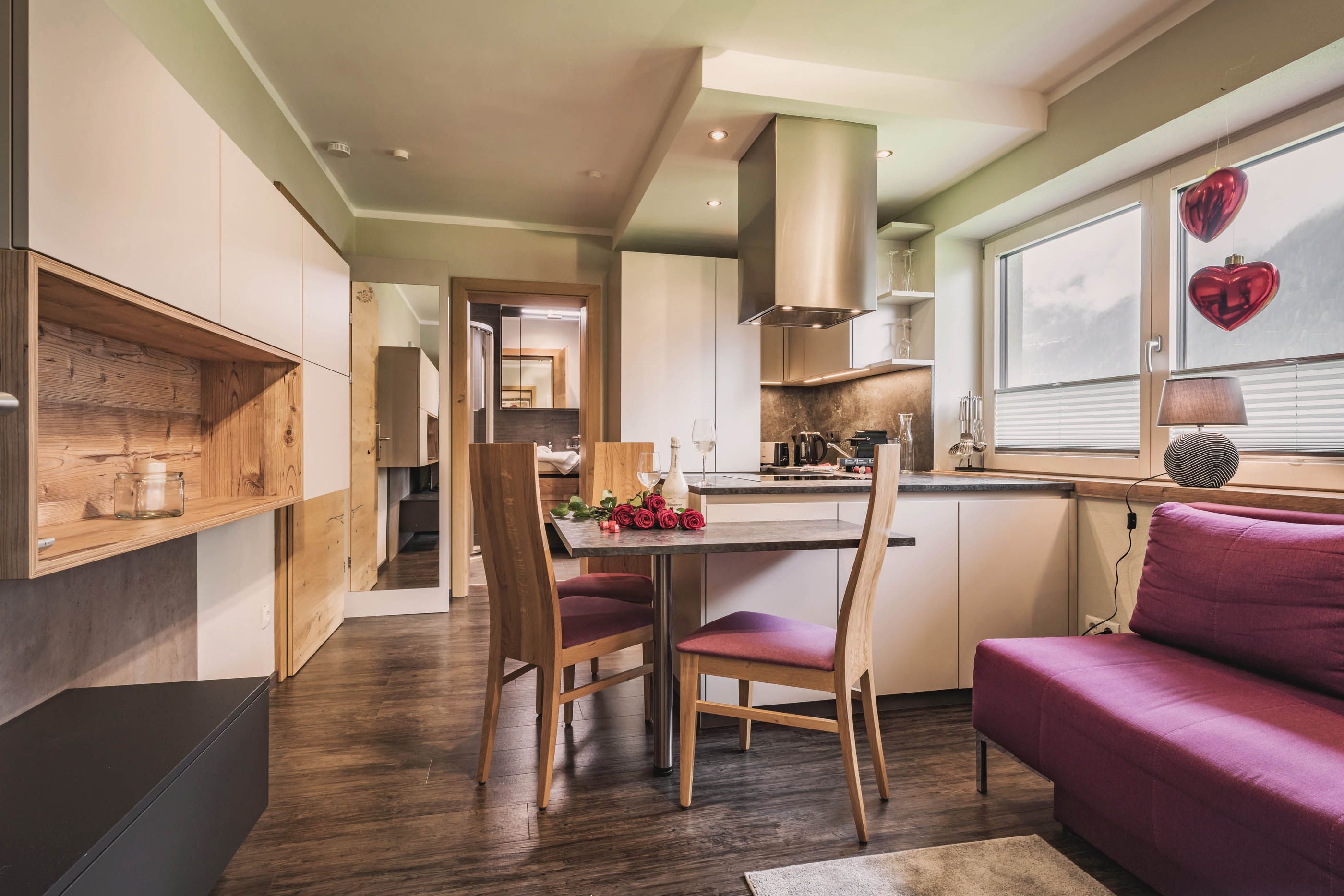 View of the living kitchen with dining table, modern chairs and red sofa in the background